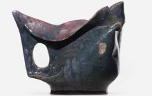Pitcher features a cut-out handle, manipulated rim, and mottled emerald, raspberry, and purple glaze. Incised script signature to underside ‘G E Ohr’. Sold for$9,375 at RAGO, May 2022.